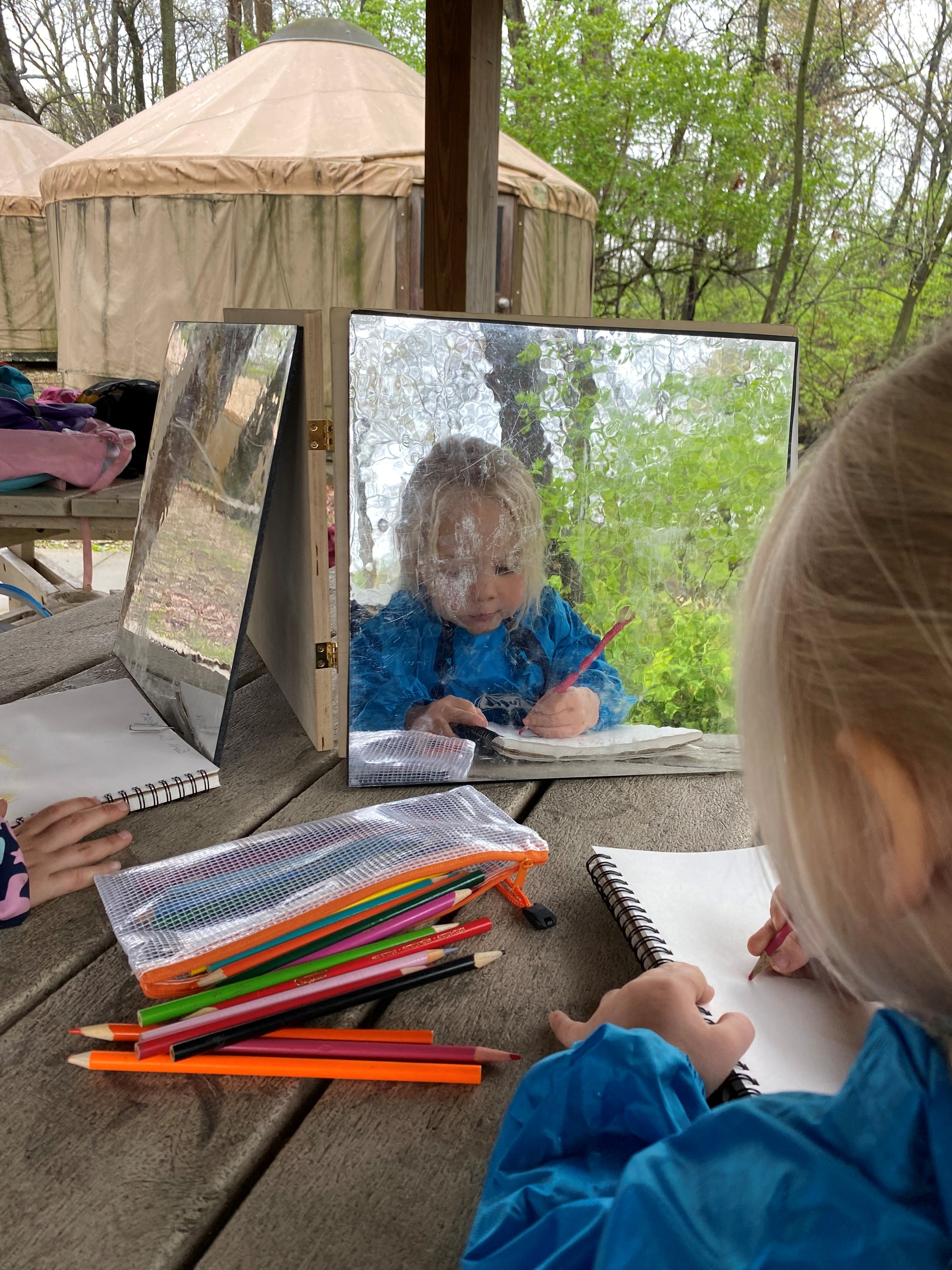 girl looking in mirrror drawing outside
